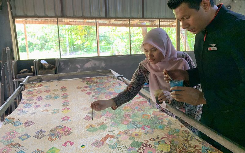 Rombongan FamTrip AirAsia mencoba membatik di Ayu Fashion, Kota Bharu, dengan mengikuti proses mencanting dan mewarnai kain secara tradisional bersama para perajin batik Kelantan.